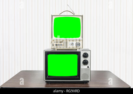 Due TV vintage sul vecchio tavolo con chroma key green schermate. Foto Stock