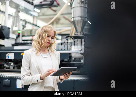 Donna che utilizza tablet a macchina in fabbrica e negozio Foto Stock