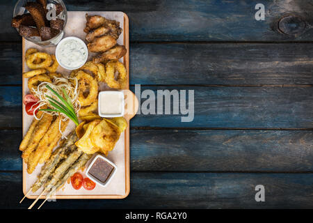 La birra snack set. Set di pesce serviti sul tagliere con la tazze, sullo sfondo di legno. Foto Stock