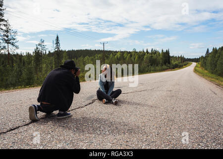 Finlandia, Lapponia, l uomo sta immagine di donna seduta su vuoto country road Foto Stock