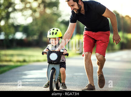 Padre insegnamento piccolo figlio di bicicletta equitazione Foto Stock