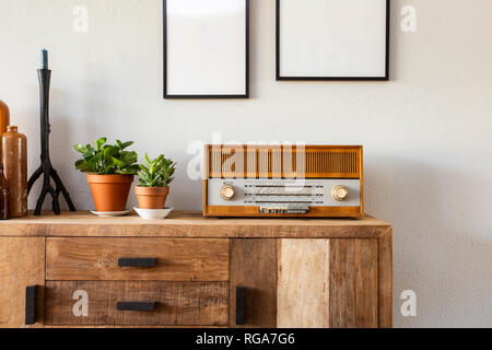 Retrò living room design con armadietto e radio lungo con piante verdi e dipinti di bianco, muro bianco Foto Stock