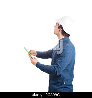 Grave fiducioso giovane ingegnere indossare casco protettivo in possesso di un PC tablet gadget cercando isolate su sfondo bianco. Foto Stock