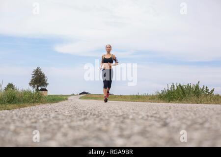 Donna matura in esecuzione in remoto paese lane in estate Foto Stock