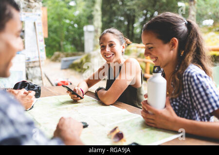 Gruppo di escursionisti seduti insieme la pianificazione di un viaggio escursionistico con una mappa Foto Stock