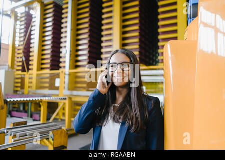 Giovane donna che lavorano nel magazzino di distribuzione, parlando al telefono Foto Stock