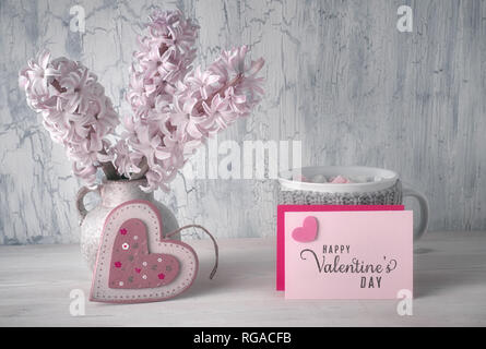 Il giorno di San Valentino ancora vita vuota le schede di carta con copy-cpace, cuore di legno, tazza di cioccolata calda e giacinto di rosa fiori su sfondo rustico Foto Stock