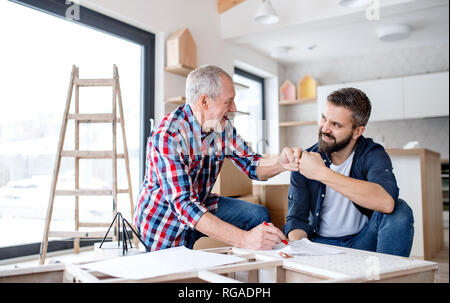 Un hipster uomo maturo con il suo padre senior di assemblaggio di mobili, un nuovo concetto di casa. Foto Stock