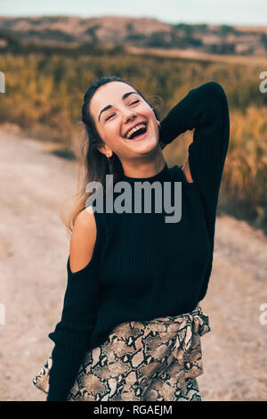 Ritratto di ridere giovane donna in natura alla moda da indossare pullover nero Foto Stock