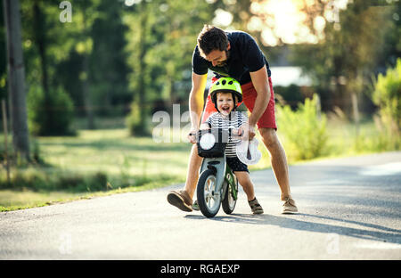 Padre insegnamento piccolo figlio di bicicletta equitazione Foto Stock