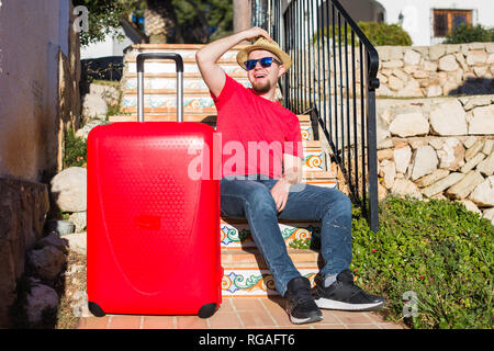 Vacanze, Viaggi, concetto di persone - il giovane uomo seduto sulle scale con le valigie Foto Stock