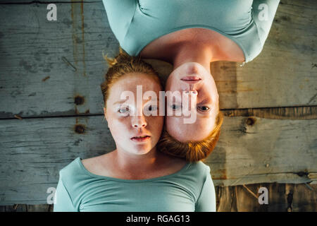 Redheaded gemelli giacente sul terreno, guardando la fotocamera Foto Stock