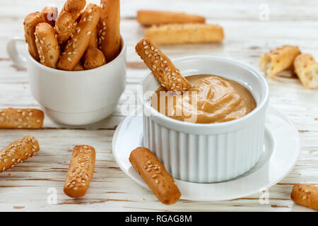 Grissini con semi di sesamo con senape dolce salsa dip. Snack Gourmet per buongustai. Messa a fuoco selettiva Foto Stock