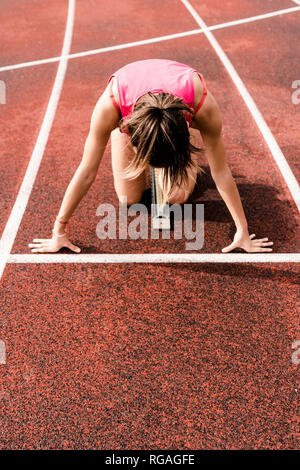 Teenage Runner in posizione iniziale sulla pista Foto Stock