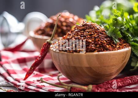 Essiccato e peperoncino frantumato in legno bowles con erbe di prezzemolo. Foto Stock