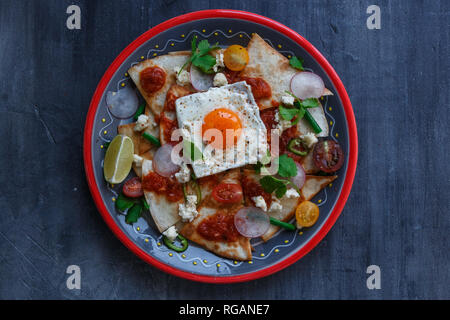 Messicano Chilaquiles tortilla con salsa di pomodoro, pollo e uovo close-up su una piastra. Vista orizzontale dal di sopra Foto Stock