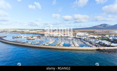 Vista aerea di Playa Blanca Rubicone marina, con barche a vela e yacht, case per vacanze, montagne vulcaniche in background Lanzarote, Isole Canarie Foto Stock