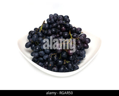 Partita di vino maturo grappoli di bacche nere nel recipiente quadrato isolato su sfondo bianco vista frontale ravvicinata Foto Stock