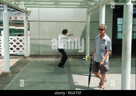 18.04.2018, Singapore, Repubblica di Singapore, in Asia - un uomo practice Tai chi in un piccolo parco al di fuori del parco della gente nel complesso Chinatown. Foto Stock