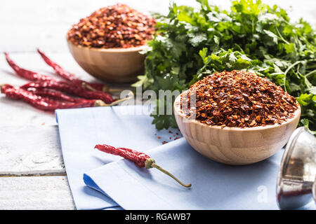 Essiccato e peperoncino frantumato in legno bowles con erbe di prezzemolo. Foto Stock