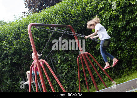 Due ragazze caucasion giocando su oscilla in un parco in un parco giochi Foto Stock