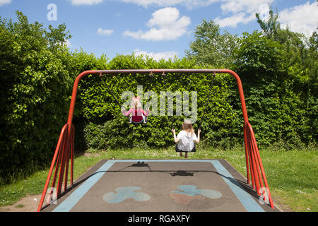 Due ragazze caucasion giocando su oscilla in un parco in un parco giochi Foto Stock