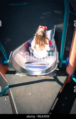 Due ragazze caucasion su una diapositiva in un parco giochi Foto Stock