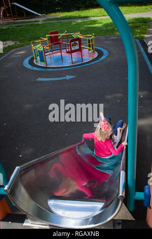 Due ragazze caucasion su una diapositiva in un parco giochi Foto Stock