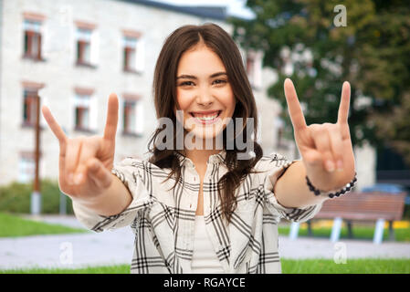 Ragazza adolescente che mostra segni di roccia oltre il campus Foto Stock