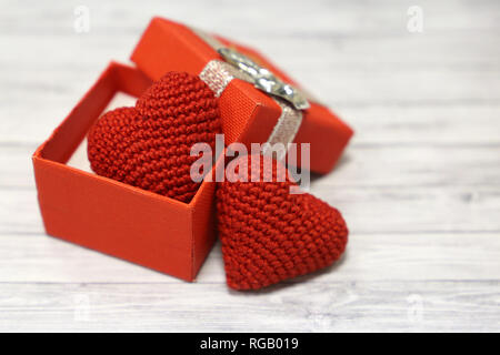 Regalo di san valentino scatola con maglia rossa cuori luce sul tavolo di legno. Romantico presente nel giorno di San Valentino, il concetto di matrimonio, l'amore cuori Foto Stock