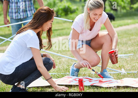 Due giovani donne come attivisti volontari sono la verniciatura di una donazione di sangue insieme poster Foto Stock