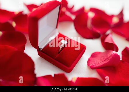 Anello diamante in velluto rosso scatola regalo sul foglio del letto Foto Stock