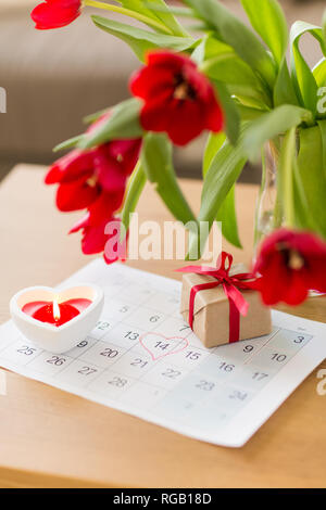 Confezione regalo, foglio di calendario e fiori sul tavolo Foto Stock