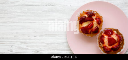 Fragola crema alla vaniglia crostate di formaggio sulla piastra di rosa, vista dall'alto. Overhead. Spazio per il testo. Foto Stock