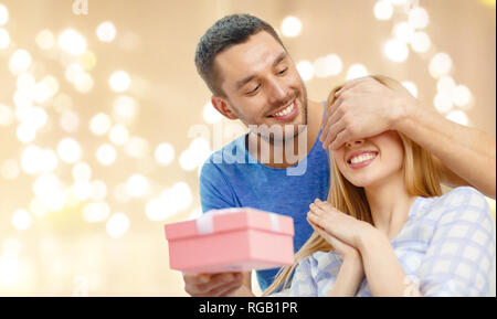 Uomo sorridente sorprese la sua fidanzata con presente Foto Stock