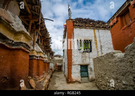 Small Alley tra bianco e arancione dipinto di case tradizionali all'interno della città murata di legna da ardere immagazzinata su tetti Foto Stock