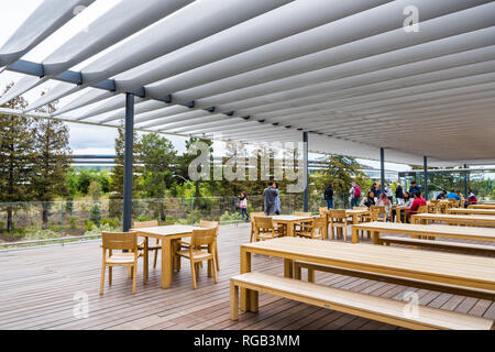 Aprile 29, 2018 Cupertino / CA / STATI UNITI D'AMERICA - Persone rilassante sul tetto del nuovo Apple Il Centro Visitatori del Parco; il nuovo Apple Corporate HQ in background; Foto Stock