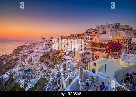 Fantastici panorami dal villaggio di Oia a Santorini Island. Tramonto idilliaco con turisti e visitatori di camminare lungo le tradizionali case greche a Oia Foto Stock
