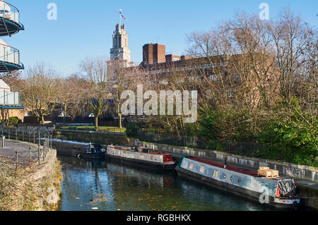 Narrowboats lungo il Limehouse tagliati in inverno, nella zona est di Londra UK, con St Anne's campanile di una chiesa in background Foto Stock