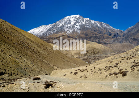 Pista sterrata che porta al villaggio di Ghemi, parzialmente visibile in lontananza. Mustang Superiore regione, Nepal. Foto Stock