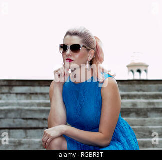 Bella bionda si sedette sui gradini, il tema delle bellissime donne Foto Stock