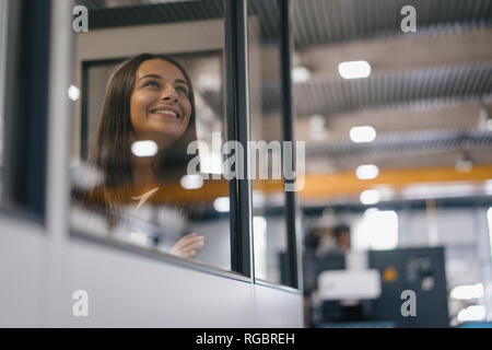 Fiducioso donna che lavorano in high tech enterprise, guardando fuori della sala di controllo Foto Stock