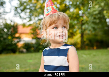 Ritratto di bambina su un compleanno garden party indossando party hat Foto Stock