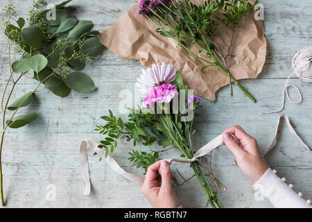 Donna di legame a mano mazzo di fiori Foto Stock