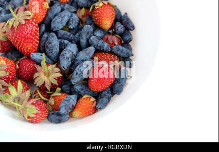 Ancora in vita, con frutta piatto assortiti con molto appetitosi mature fragola e caprifoglio isolato ob sfondo bianco studio shot top view closeup Foto Stock