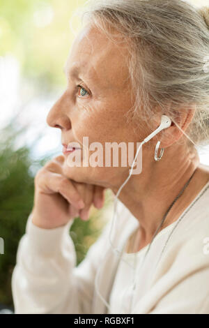 Vista di Profilo di donna senior con gli auricolari Foto Stock