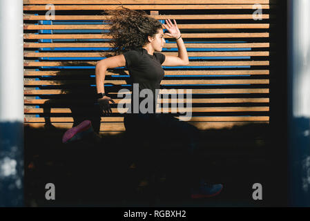 Attività sportive giovane donna che corre lungo la boiserie in legno Foto Stock