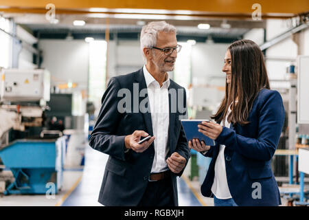 Proprietario di una donna in high tech enterprise, avente un incontro in officina in fabbrica Foto Stock