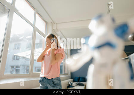 Giovane donna ascoltando musica con le cuffie a casa Foto Stock