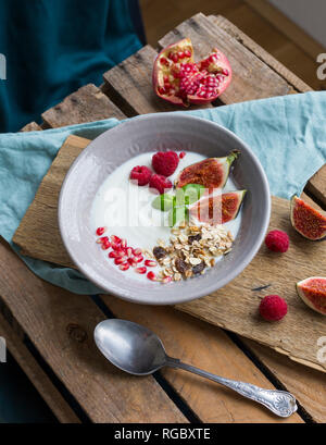 Ciotola di yogurt naturale con frutta muesli, lamponi, fichi e i semi di melograno Foto Stock